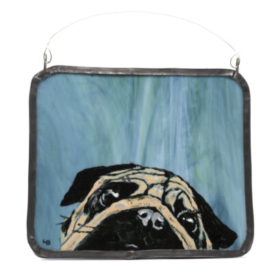 A stained glass wall art plaque featuring a hand-painted pug head peeping over the bottom of the panel. Design painted on real aqua-green-blue stained glass and framed in real blacked and waxed lead came.