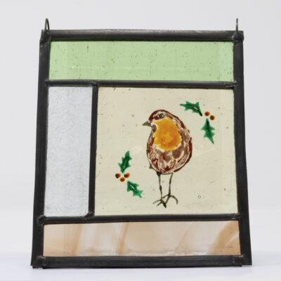 Small stained glass panel with rectangles of different coloured glass and featuring a hand-painted robin and holly