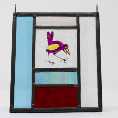 Real mini stained glass window with red, pink and blue glasses and featuring a hand-painted pink bird in the centre.