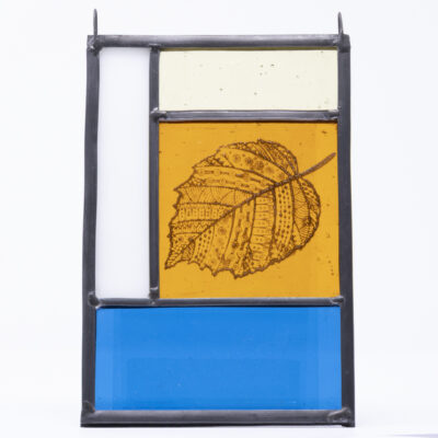 Mini stained glass panel made traditionally using lead and coloured glasses in amber, blue, yellow and white and featuring a stencilled black leaf design.