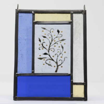 Mini stained glass panel traditionally made with lead and solder, featuring rectangles of blue, yellow and white glass and a hand-painted tree in the centre in black and yellow.