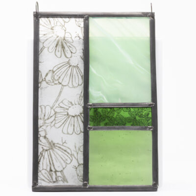 A small, traditionally made stained glass art panel featuring real stained glass rectangles in green tones and a daisy design on clear glass down the left.